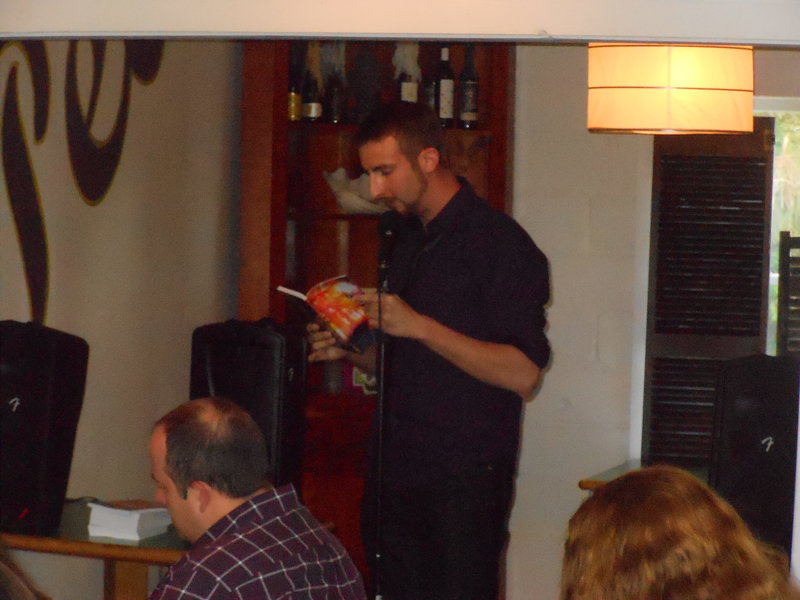 Reading a part of my story.  They couldn't get the microphone stand to stay at my height, so I had to "Double-task."